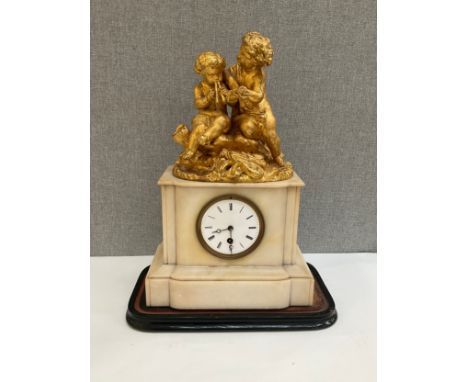 A 19th Century French alabaster mantel clock, gilded figural top, cracked to reverse, glass missing, 42cm tall 