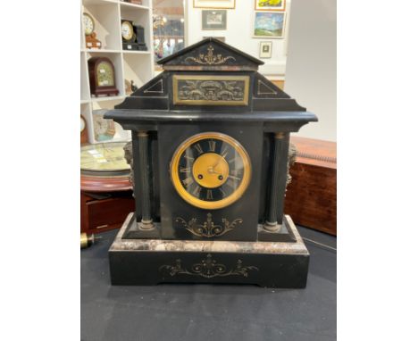 A circa 1900 black slate and marble mantel clock with Roman chapter ring, brass relief plaque to top, with pendulum 