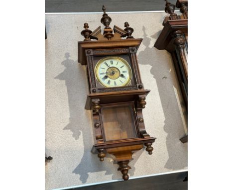 An early 20th Century Ansonia Clock Company wall clock with stepped bracket form case, carved detail to door, finial top, 64c