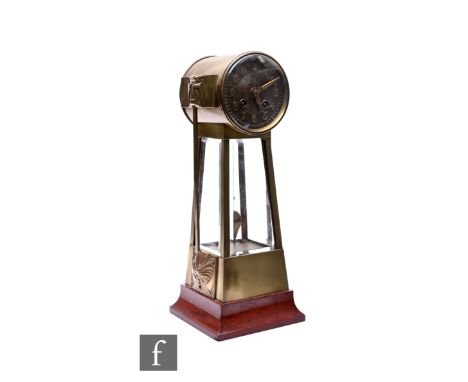 An Arts &amp; Crafts brass mantle clock, the circular dial with eight day striking movement over glass bevelled sides, Arabic