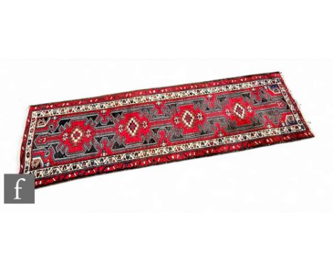 A Heriz style runner, the four bordered pole medallion on a red ground within a multi floral running border, 252cm x 79cm.
