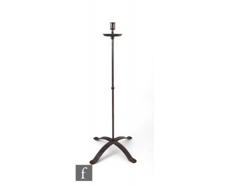 A wrought iron floor standing candlestick, with circular shaped drip tray over a strapwork cruciform shaped base, height 118c