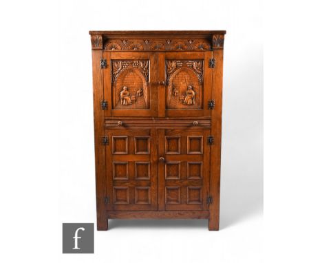 A 1930s or later oak cocktail cabinet, fitted interior enclosed by a pair of arch carved doors detailed with figures within b