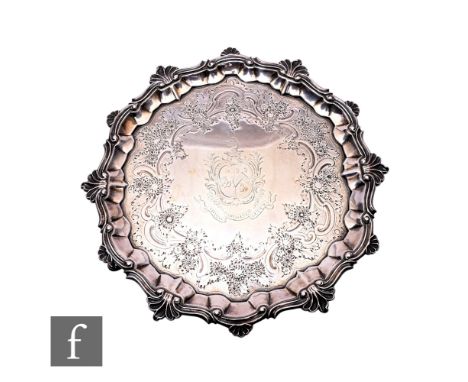 A George II hallmarked silver salver, raised on three pad feet, with later foliate engraved decoration, around central crest,