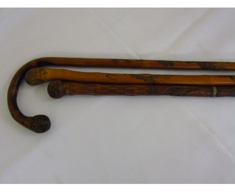 Two carved bamboo walking sticks plus one carved bamboo walking stick.
