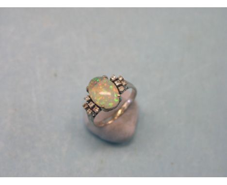 An 18ct. white gold, opal and diamond chip ring, large oval opal, claw settings