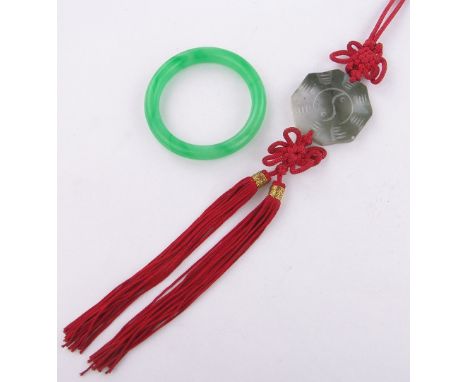 A Chinese green jade bangle,& a Chinese jade pendant on silk cord (2)