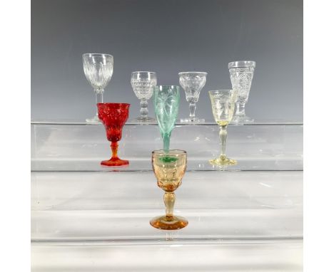 A charming set of eight tiny glass cups that includes one red, one green, one yellow, and one amber colored cup, accompanied 