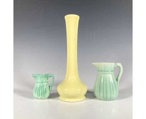 A stylish pair of teal creamers in varying sizes, each elegantly decorated with ridged details, alongside a smooth yellow vas