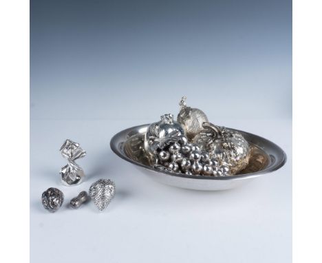 A stylish metal bowl filled with an assortment of metallic fruit, including a lemon, strawberry, pomegranate, peanut, walnut,