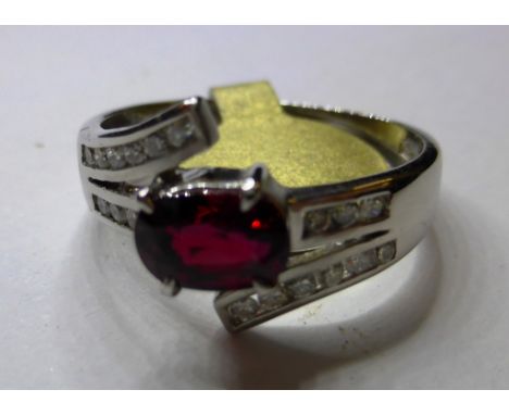 An 18ct white gold, ruby and diamond cross over ring (size L)