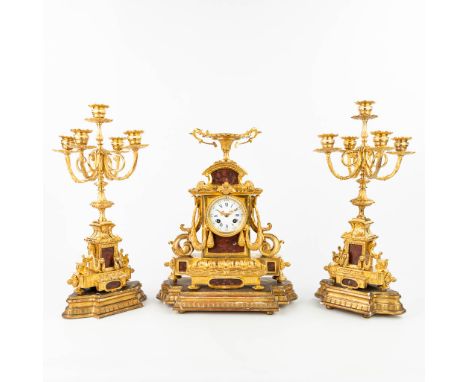 A three-piece garniture clock, inlaid with red marble and standing on wood bases. Height candelabra: 43 cm. Sizes without bas