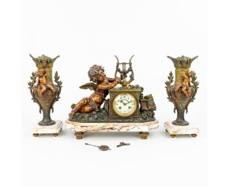 A three-piece mantle clock made of spelter and decorated with putti. (16 x 37,5 x 33 cm)