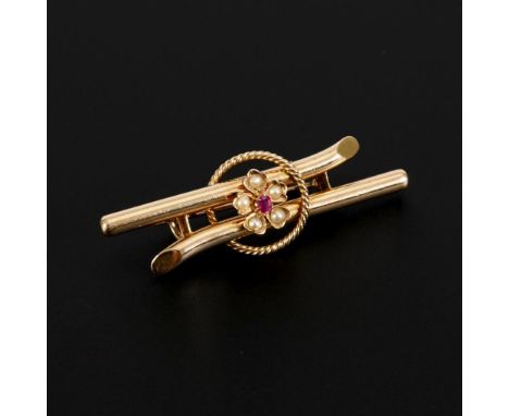 Brosche mit Rubin und Saatperlen, um 1900.             Roségold 585 gestempelt. 4,3 x 1 cm. 3,5 g.             Auf Doppelsteg