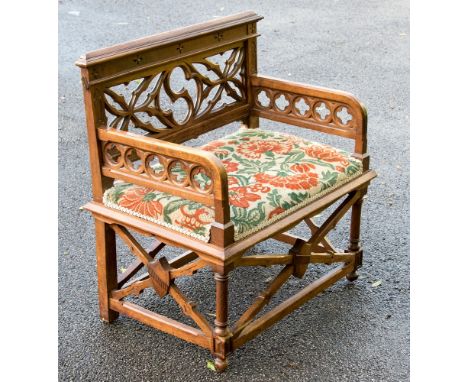 A Gothic Revival walnut bench or armchair, the wide cushioned seat below a pierced back of S quatrefoil cartouche flanked by 