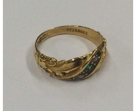 An emerald and diamond ring with scroll decoration set in 18 carat gold. Approx. 3 grams. Est. £50 - £80.