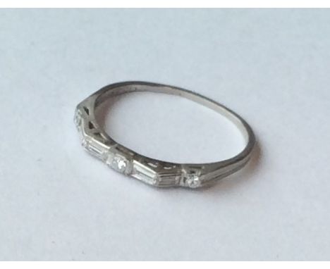 An unusual platinum and diamond half eternity ring set with baguette cut stones. Approx. 2.1 grams. Est. £200 - £300.