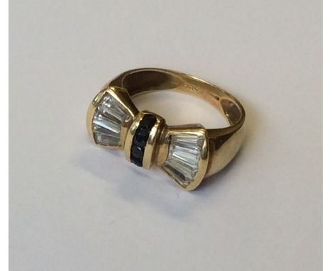 A sapphire and diamond bow shaped cluster ring in 18 carat gold mount. Approx. 5.5 grams. Est. 250 - £350.
