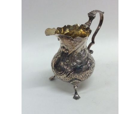 A Georgian silver embossed helmet shaped cream jug decorated with flowers and leaves. Approx. 71 grams. Est. £70 - £80.