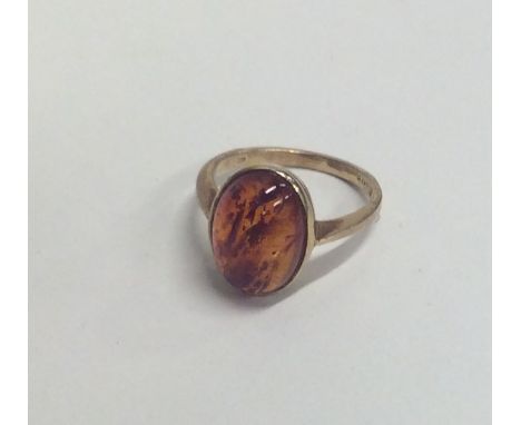 An amber single stone ring in rubover mount. Approx. 3.3 grams. Est. £30 - £40.