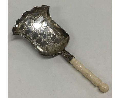 A Georgian silver bright cut caddy shovel decorated with flowers and leaves to turned ivory handle. Approx. 7.7 grams. Est. £