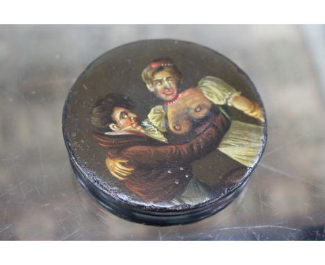 A 19TH CENTURY CIRCULAR PAPIER MACHE SNUFF BOX, the lid suggestively painted with a couple dancing (AF) 9cm diameter