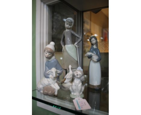 FOUR LLADRO PORCELAIN FIGURINES to include a girl with a duck drinking water from a pail, a girl holding a piglet, a boy hold