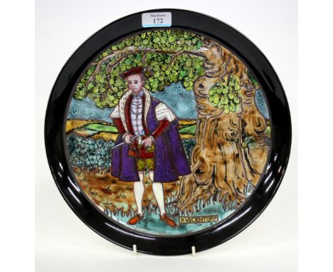 A POOLE POTTERY CHARGER depicting a 16th century scene of a gentleman in purple robes stood beneath an oak tree, signed to th