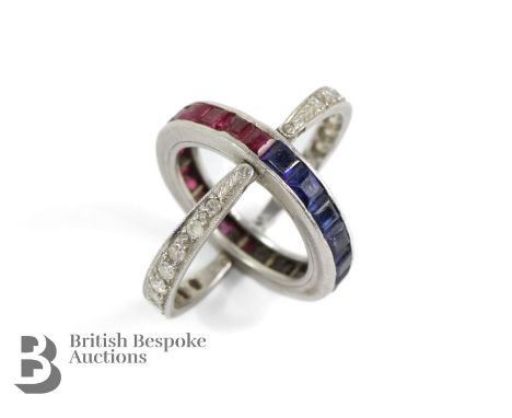 A platinum swivel guard eternity ring, with a half hoop of rubies and a half hoop of sapphires, all channel set to a central 