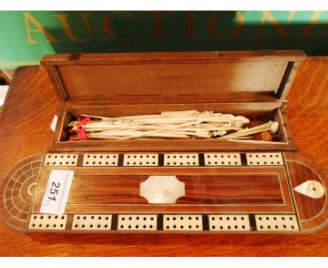 An early 20th century cribbage board inlaid with mother of pearl, together with a box containing a quantity of ivory toothpic
