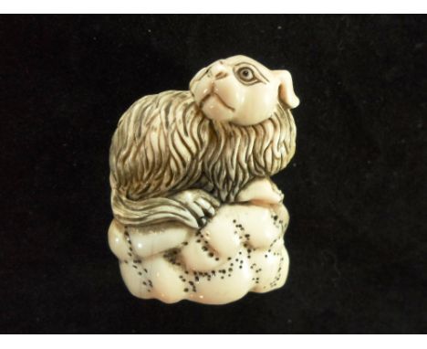 A Meiji period ivory netsuke of a dog perched on a rocky outcrop, 5cm tall, signed