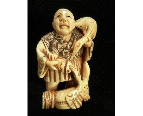 A late 19th century Japanese ivory netsuke of a man holding a fish with a pair of storks, 5cm tall, signed