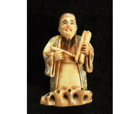 A late 19th century Japanese ivory netsuke of a scribe, standing with pen and paper to hand, 5.1cm tall, signed