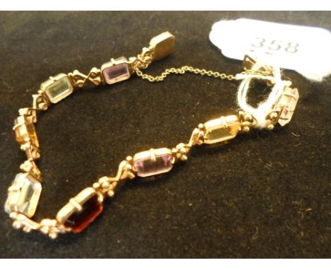A multi-gem set line bracelet, the yellow metal crossover bands set with step-cut, cut-cornered rectangular stones including 