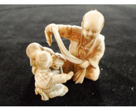 A 19th century Japanese carved ivory okimono netsuke of a man holding a scarf beside two playing children, 3.7cm x 3.17cm, si