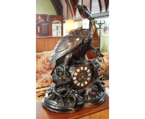 A large continental carved hardwood mantel clock, fashioned as a bird of prey on a rocky outcrop, the dial bearing enamel rom