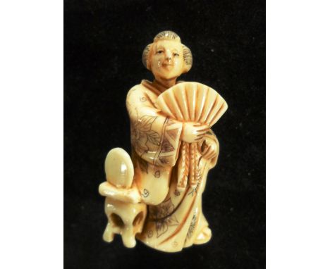 A late 19th century Japanese ivory netsuke of a lady in traditional dress holding a fan, 4.8cm tall, signed