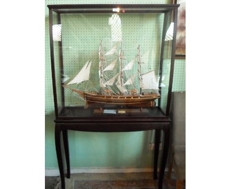 A hand built scale model of the Cutty Sark, the three-masted cutter on conforming wooden stand in a bespoke floor standing di