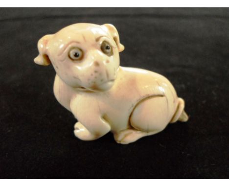 A late 19th century Japanese ivory netsuke of a seated puppy, looking to the left, 3.5cm tall, signed