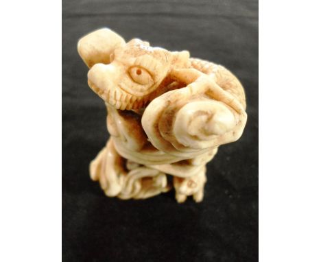 A late 19th century Japanese okimono netsuke of a dragon perched on rocks, with a dog at the base, 5cm tall, unsigned