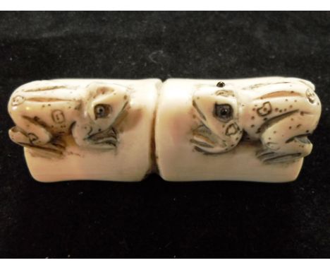 A Japanese ivory netsuke formed of two frogs, late 19th century, facing each other on a stem of bamboo, 5.5cm, signed