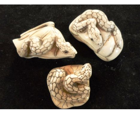 Three Meiji period ivory carved netsuke, each of a snake with applied eyes, 4.7cm, 5.8cm & 3.7cm, all signed