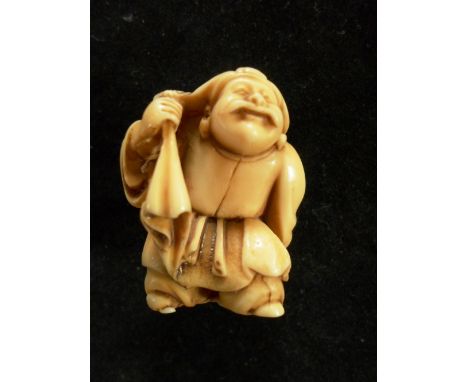 A Meiji period ivory carved netsuke of an elderly man carrying a bag and hammer, 3.6cm tall, unsigned
