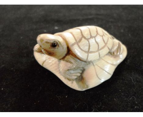 A late 19th century Japanese carved ivory netsuke of a tortoise on a curved leaf, 5cm, signed
