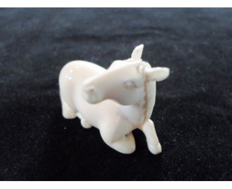 A Japanese ivory netsuke of a recumbent horse, his head turned to the right, 4cm, signed