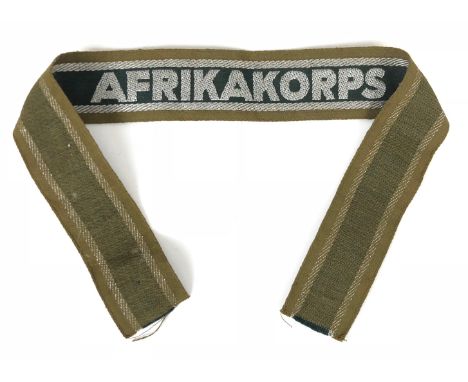 German Third Reich WW2 Afrika Korps cuff title.  Good tan cotton band with silver wire block letters embroidered on dark gree