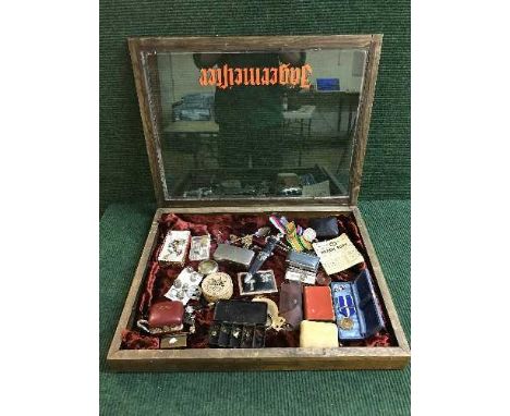 A display case of spoon, WWI medals, Kosovo medal, Dirk pin badges, military buttons, wrist watches, lighter, ration book etc