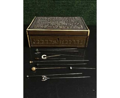 A carved trinket box containing a quantity of hat pins, including two silver examples by Charles Horner (Q)