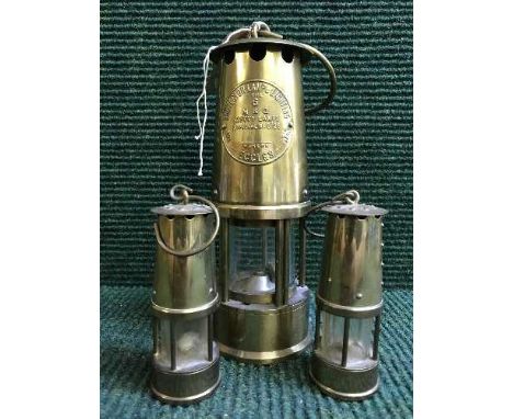An Eccles Protector miner's lamp and two miniature brass miner's lamps 