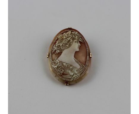 A yellow metal mounted oval shell cameo pendant/brooch, the shell carved with a profile bust of Bacchus, his hair and robe ad